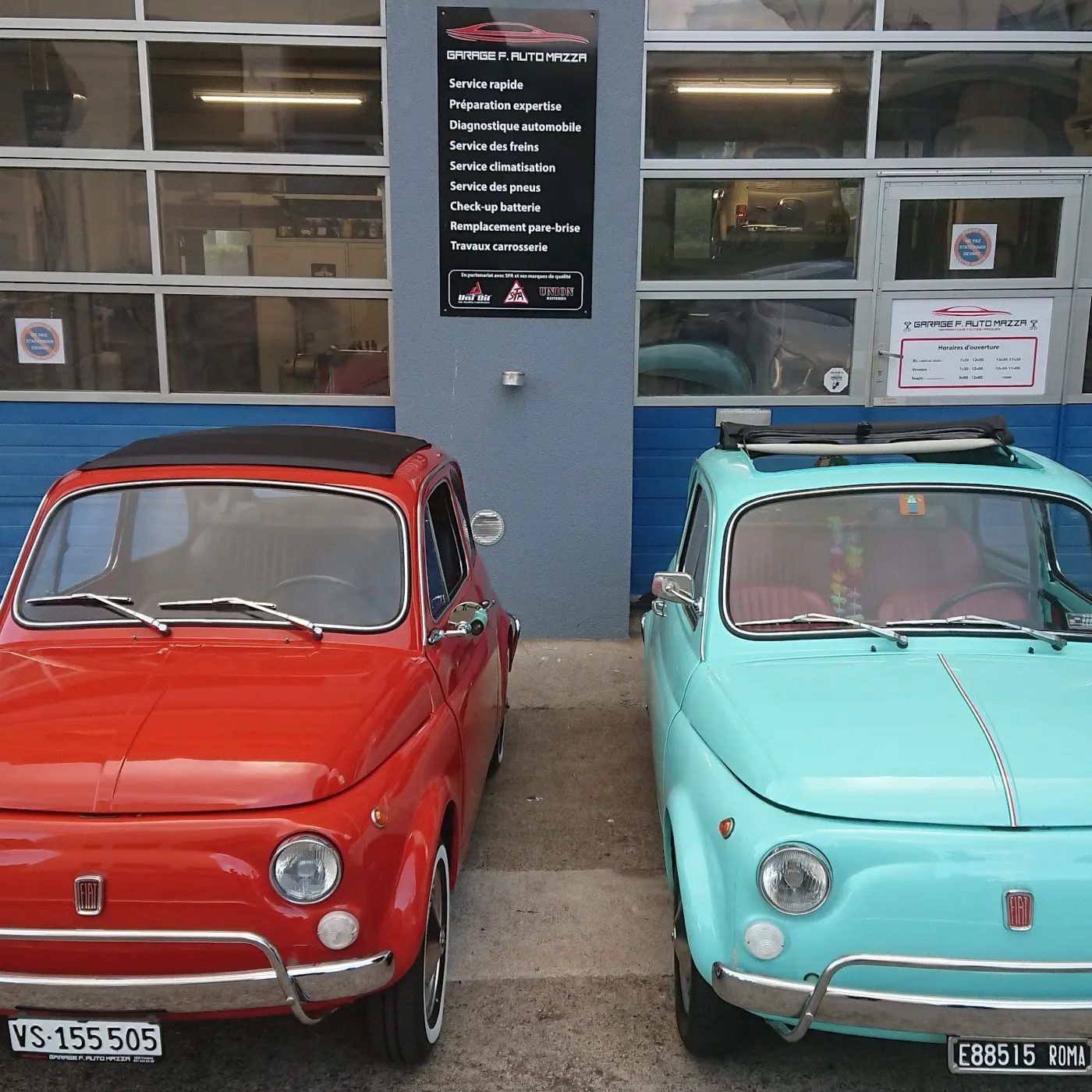 Deux Fiat 500 classiques devant le panneau de services du garage